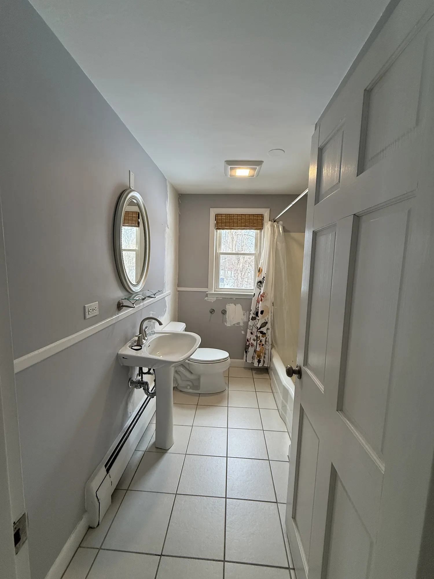 Completed bathroom repaint with soft gray walls, white trim and tile floor