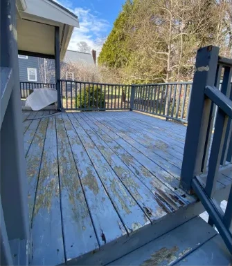 Before: the same deck with weathered blue paint and exposed wood