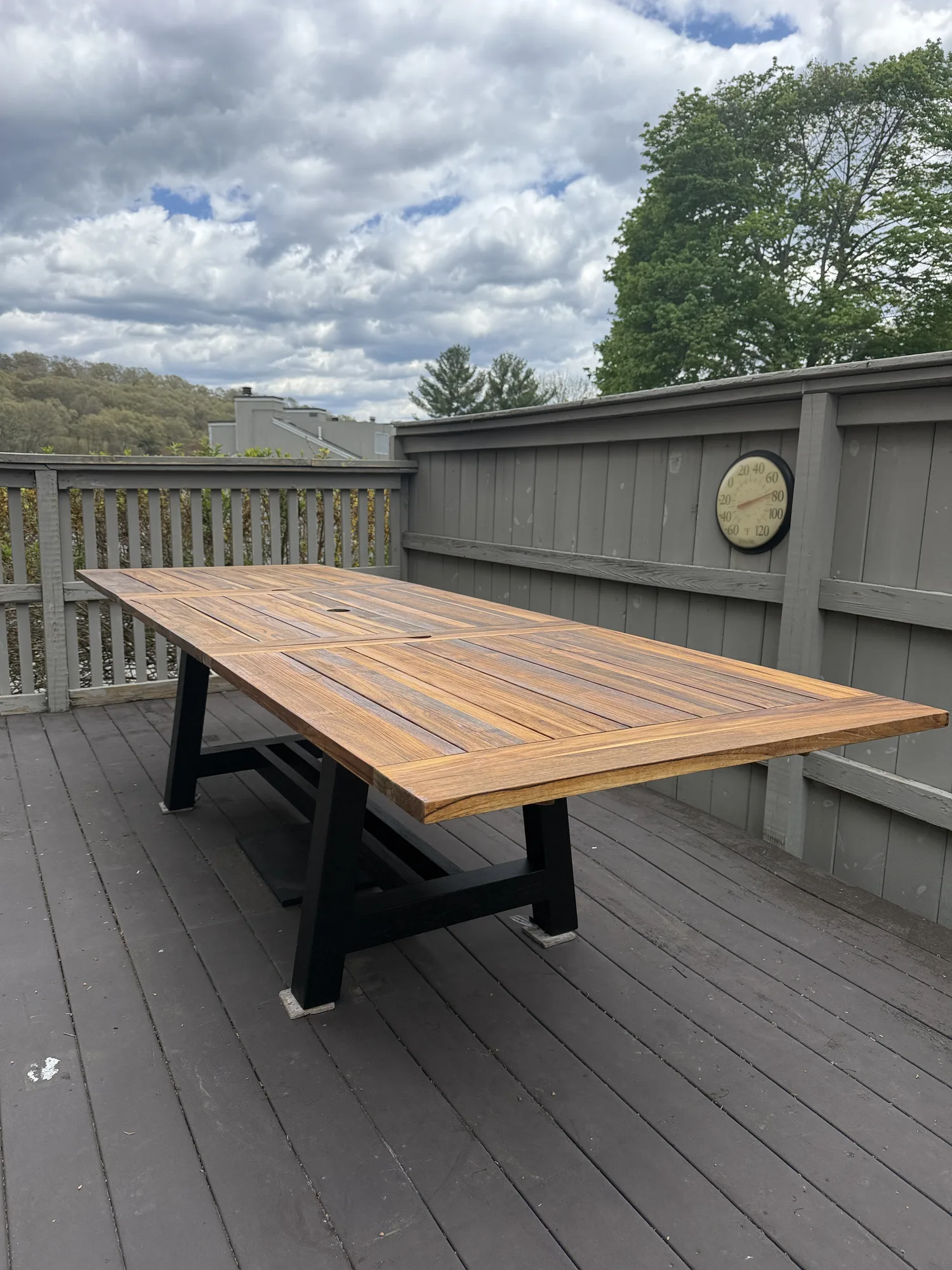 Refinished outdoor dining table with a warm, even wood finish on a deck